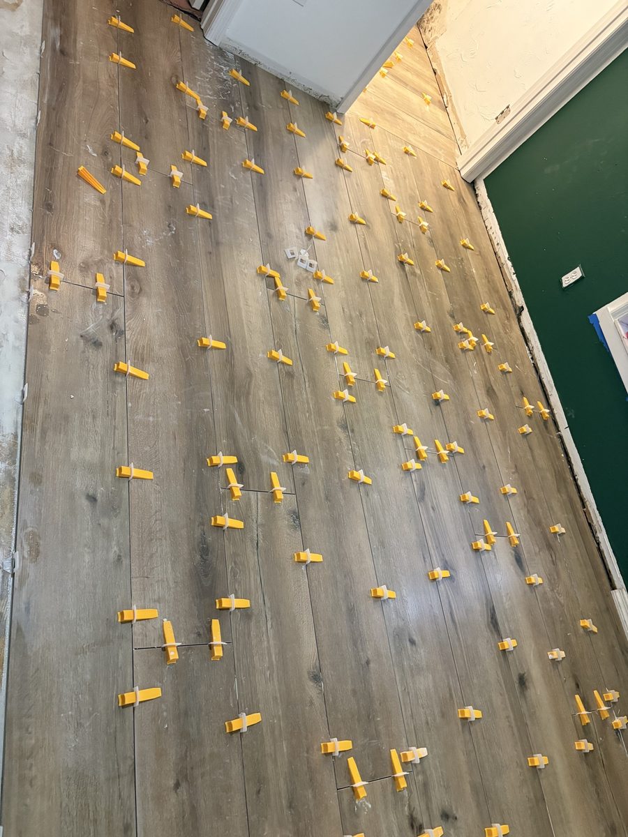 Plank tile floor installation with leveling wedges