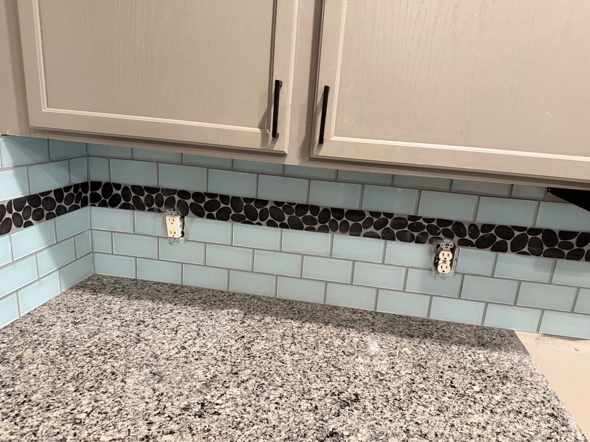 Glass subway tile backsplash with pebble accent